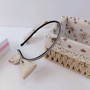 Detail of champagne silk bow headband with sparkling white rhinestones and black frame
