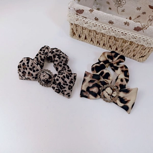 Detail of leopard print scrunchies with rhinestone buckle on a clean white surface
