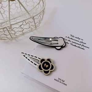Close-up of floral hair clips with black and white petals and elegant metal details