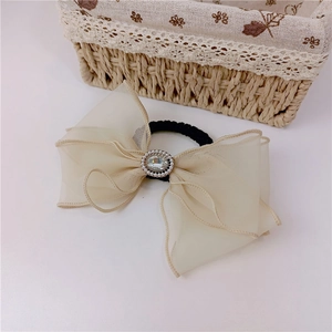 Détail d'un chouchou papillon en organza beige avec strass centraux et perles