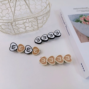 Vue détaillée de pinces à cheveux coeur en résine mate avec motif lettre B, lot de trois