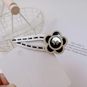 Black resin flower hair clip with white leather trim and golden bow detail for women