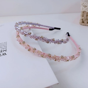 Détail de serre-têtes en cristal rose et violet avec perles dorées sur un livre blanc