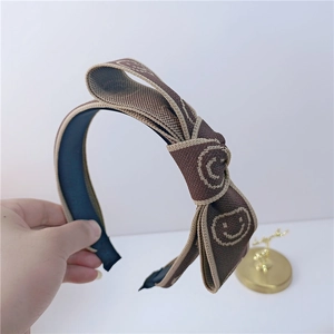 Détail du bandeau à nœud marron tricoté avec motif smiley et doublure antidérapante