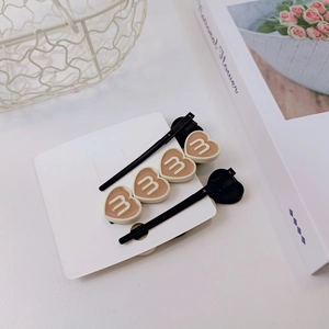 Détail de deux pinces à cheveux style coréen en forme de cœur avec lettre M blanche