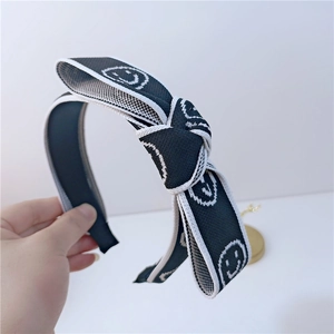 Détail d'un serre-tête tricoté avec un nœud noir orné de motifs smiley blancs élégants