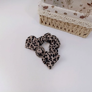 Detail shot of leopard print scrunchie with sparkling rhinestone buckle on white background