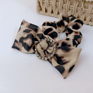 Close-up of leopard print bow hair tie with a sparkling rhinestone circular buckle
