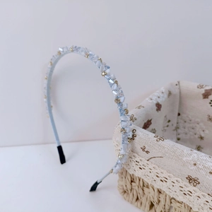 Détail du serre-tête bleu clair avec pierres mates blanches et strass dorés fins
