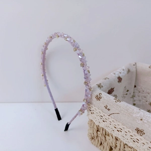 Détail de perles en cristal lavande et accents dorés sur un serre-tête fin