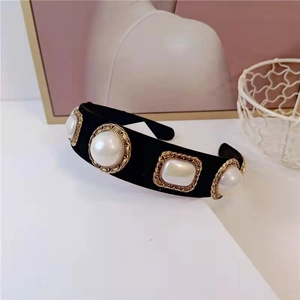 Detailed close-up of velvet headband with faux pearls and golden braided metal base