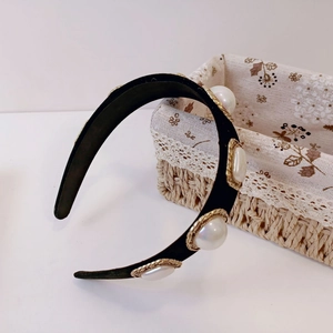 Close-up of velvet headband with four large pearls and gold woven metal borders