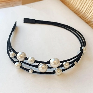 Detailed macro view of triple-layered woven headband with vintage cream pearls