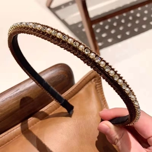 Close-up of elegant pearl and rhinestone inlay on a dark brown velvet headband hair accessory