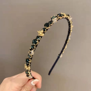 Detail of dark green crystal headband with gold floral accents and shiny rhinestones