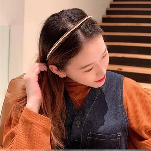 Detail showing faux pearls on a slim dark headband worn in natural hair for styling