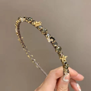 Detail of vintage gold headband with emerald rhinestones and small pearls