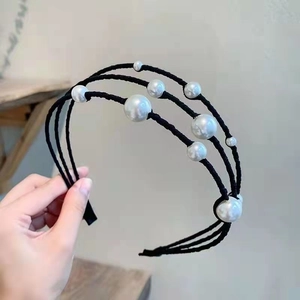 Detail of a minimalist triple-layer headband featuring elegant white pearls on black cords