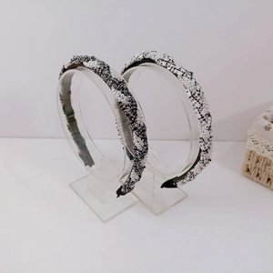 Detail view of two tweed headbands with white pearls on a transparent display stand