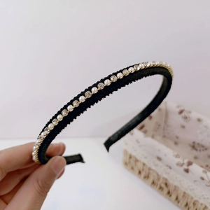 Close-up of elegant black headband featuring white pearls and sparkling rhinestones