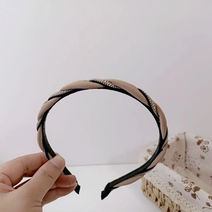 Detailed close-up of a braided beige headband with sparkling silver rhinestone trim details