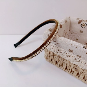 Close-up of a brown fabric headband featuring elegant pearl and rhinestone embellishments