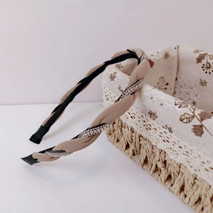 Detailed view of khaki and black braided headband with shimmering silver rhinestones