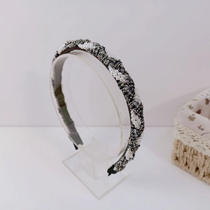 Detail of tweed headband featuring intertwined black and white fabric and faux pearls
