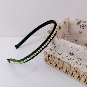 Detail of dark green velvet headband featuring elegant white pearls and sparkling rhinestones