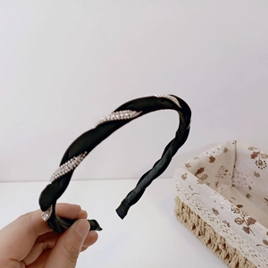 Detail of a black braided headband featuring elegant white pearls and soft satin texture