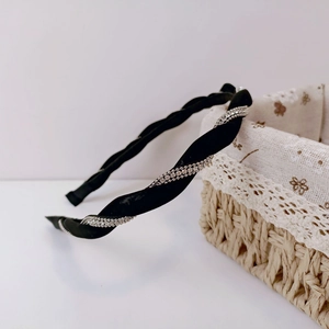 Detail view of a black twisted satin headband with shiny silver rhinestone chain accents