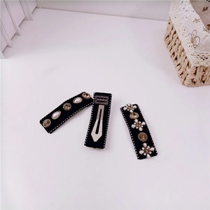 Detail of three black vintage baroque hair clips with pearls and rhinestones on white table