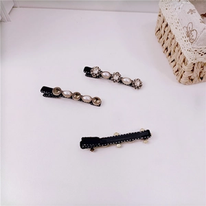 Detail of vintage black polka dot hair clips with pearls and rhinestones on white background