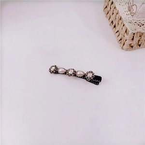 Close-up of retro black fabric hair clip with square rhinestones and teardrop pearls