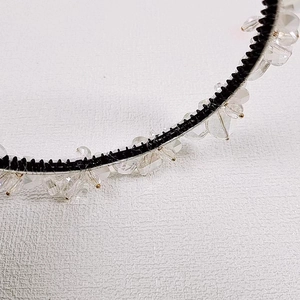Detail of transparent crystal beads hand-wired on a black plastic headband