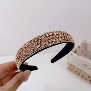 Pink rhinestone padded headband with sparkling crystals held in hand for hair styling