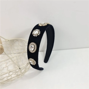 Detail view of a black velvet headband featuring luxury crystal rhinestones in gold setting