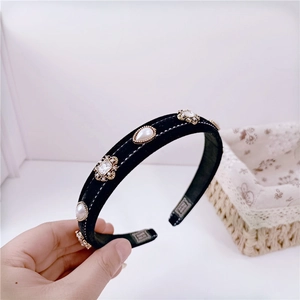 Detailed macro view of black velvet headband with vintage pearls and sparkling rhinestones