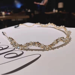 Detail showing wavy gold metal headband with pearls and rhinestones on decorative card