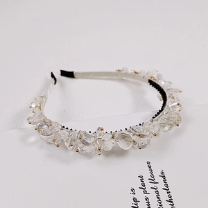 Macro detail of large faceted crystal beads on a refined handmade headband with gold pins