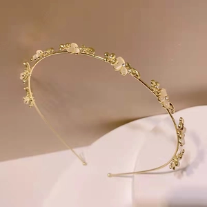 Dettaglio di un'elegante fascia dorata con fiori in pietra occhio di gatto e piccoli strass