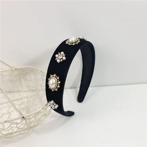 Detailed close-up of a wide black velvet headband with sparkling rhinestone and pearl charms
