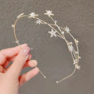 Detailed close-up of a gold starry headband featuring sparkling crystals and white pearls