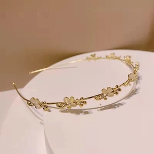 Dettaglio del cerchietto dorato con fiori in opale e piccoli strass luminosi su base bianca