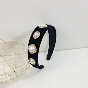 Close-up of black velvet wide headband with large pearls and sparkling rhinestones