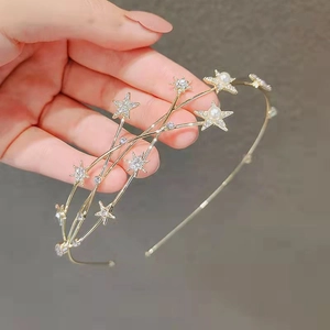 Detailed view of a gold star headband with sparkling rhinestones and white pearls