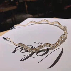Elegant gold wave headband with pearls and rhinestones on a white magazine background