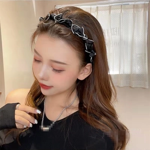 Détail d'un serre-tête élégant en tissu noir avec nœud papillon et liseré blanc chic