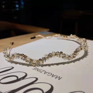 Macro shot of wave-shaped headband with pearls and rhinestones on a magazine background