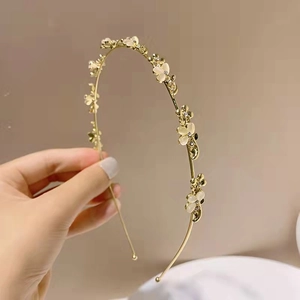 Elegante cerchietto dorato con fiori di opale bianco e accenti di cristallo su fondo neutro